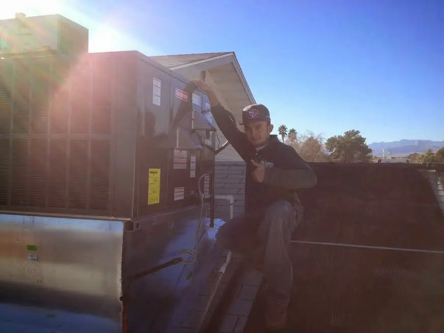 HVAC technician performing Heat Pump Repair on a rooftop unit in Pelham